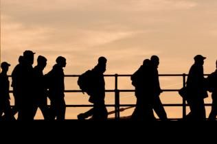 Dark silhouettes of people walking across a bridge