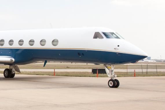 A blue and white Gulfstream airplane sits on a tarmac at an airport