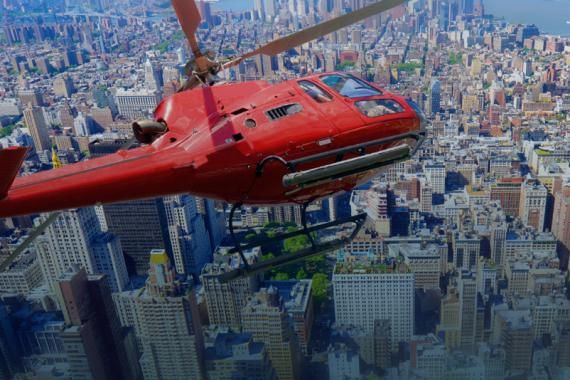 A red helicopter flies over city buildings
