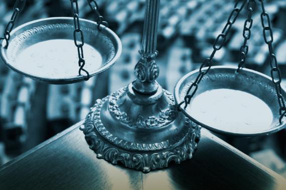 An ornately carved scale of justice sits at the edge of a table