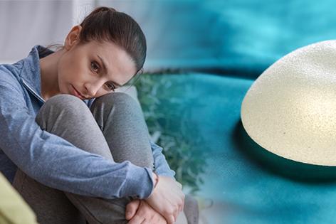 A young woman is sitting alone with her legs against her chest and her arms around her legs. She appears to be lost in thought