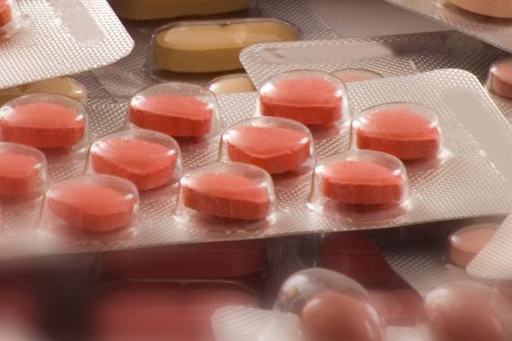 Orange pills in plastic pop-out packaging is lying above several packages of similar pills