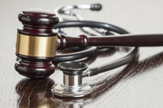 A judge's gavel and a doctor's stethoscope are placed side-by-side on a table